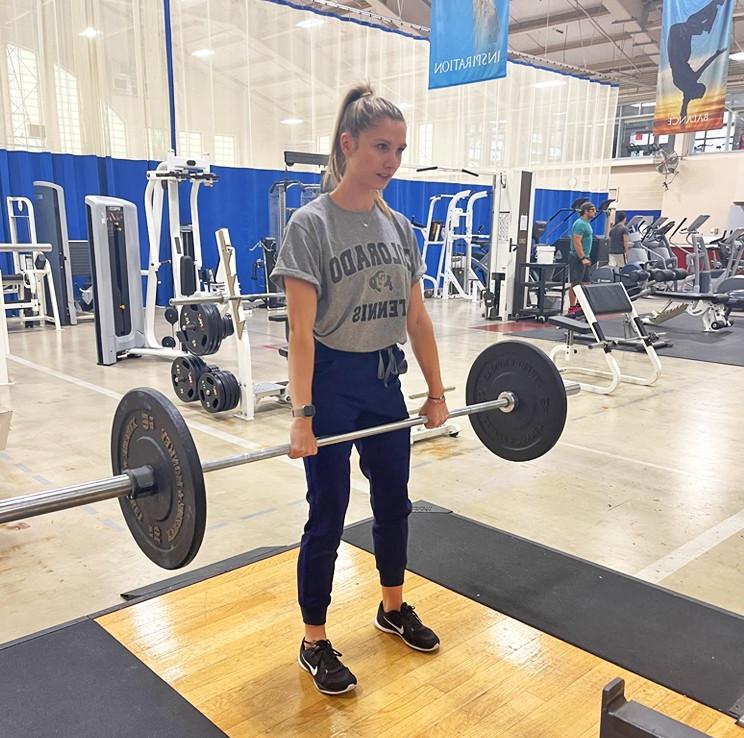 A student performing a Romanian deadlift with a barbell