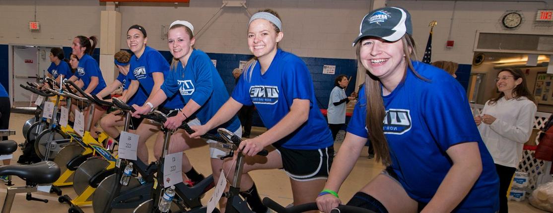 A row of students biking on stationary bikes during a Cycle for Life event