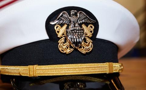 A military captain's hat with American flags in the background
